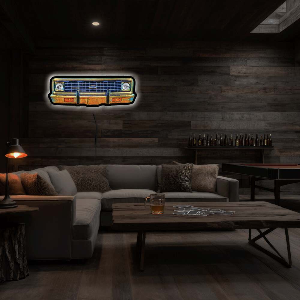 A glowing neon-style sign of a vintage 1970 A neon sign depicting a 1970 K10 front grille, featuring a glowing blue grille, chrome bumper, and white headlight glow, set against a dark background.  mounted on a dark wood-paneled wall in a dimly lit modern living room with a sectional sofa and wooden coffee table.
