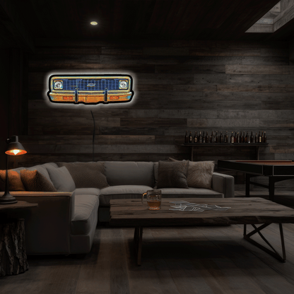 A glowing neon-style sign of a vintage 1970 A neon sign depicting a 1970 K10 front grille, featuring a glowing blue grille, chrome bumper, and white headlight glow, set against a dark background.  mounted on a dark wood-paneled wall in a dimly lit modern living room with a sectional sofa and wooden coffee table.