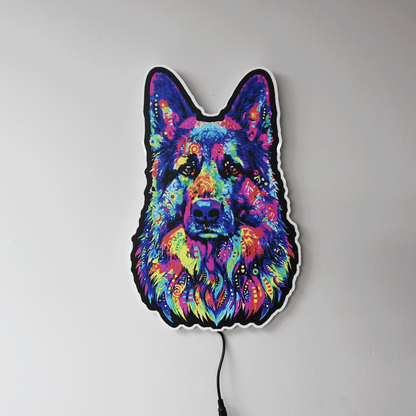 A colorful LED wall light shaped like a German Shepherd dog's face, featuring a vibrant neon pattern in blue, pink, purple, yellow, and green, mounted on a plain light gray wall.