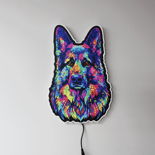 A colorful LED wall light shaped like a German Shepherd dog's face, featuring a vibrant neon pattern in blue, pink, purple, yellow, and green, mounted on a plain light gray wall.