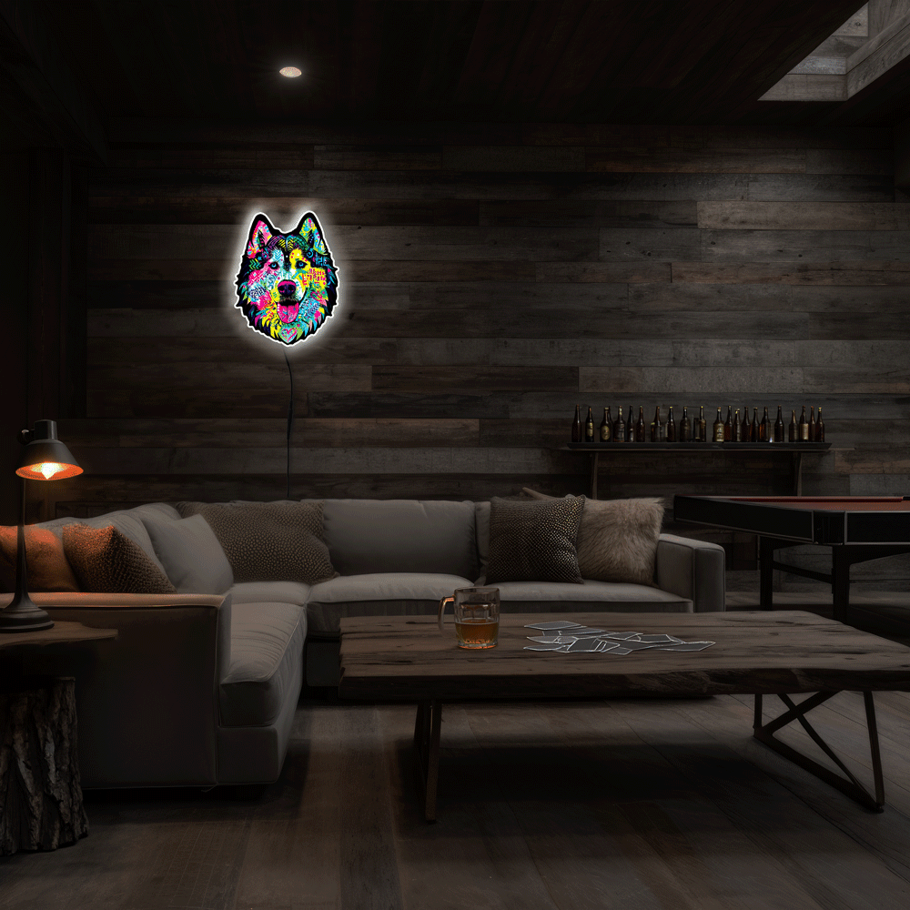 A colorful neon-style wall art piece shaped like a dog head hangs on a dark wood-paneled wall in a dimly lit living room with a sectional sofa, coffee table, and lamp.
