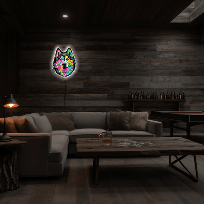 A colorful neon-style wall art piece shaped like a dog head hangs on a dark wood-paneled wall in a dimly lit living room with a sectional sofa, coffee table, and lamp.