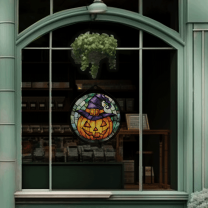 Jack-o'-lantern witch hat sign displayed unlit, hanging in a shop window at night