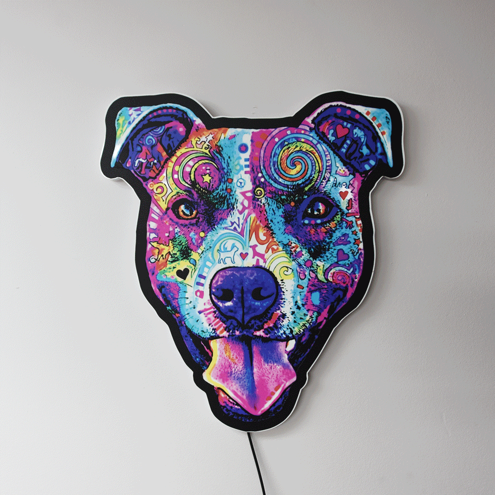 A wall art piece shaped like a Colorful Smiling Pit Bull Face with tongue hanging out, featuring a vibrant psychedelic pattern in shades of purple, blue, pink, yellow, and green, mounted on a plain light gray wall.
