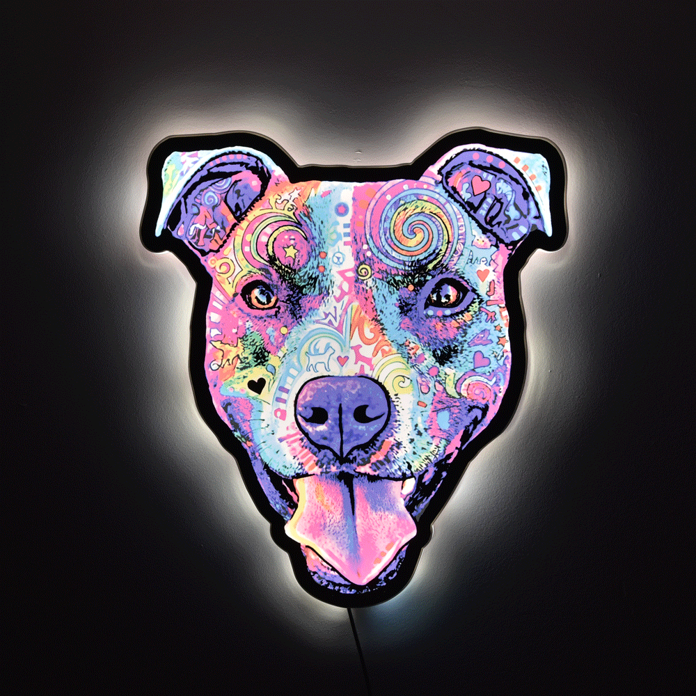 A pop-art style Colorful Smiling Pit Bull Face with tongue hanging out wall light or sign with a black outline, glowing against a dark background. The design features swirling patterns and bright neon-like colors including pink, purple, blue, yellow, and orange.