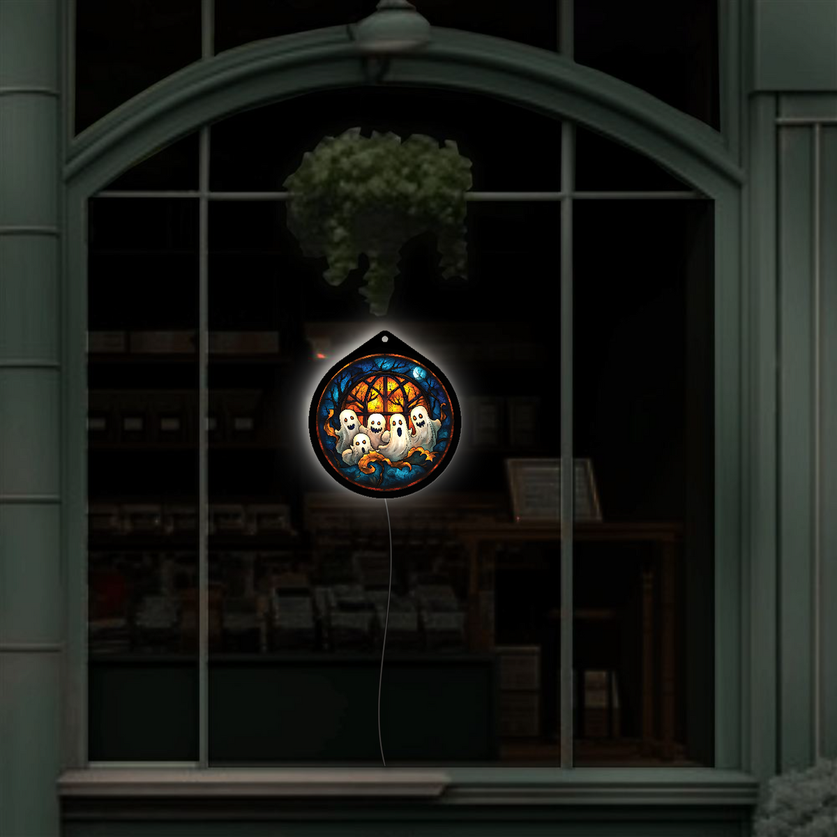 Ghost family LED sign glowing, hanging in a shop window display at night
