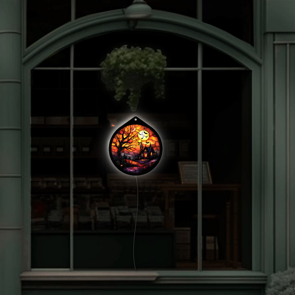 Haunted tree and moon LED sign glowing, hanging in a shop window display at night