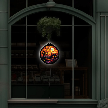 Haunted tree and moon LED sign glowing, hanging in a shop window display at night
