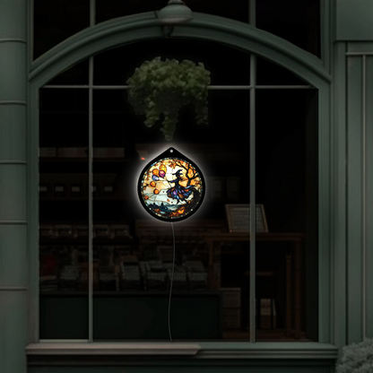 Flying witch with balloons LED sign glowing, hanging in a shop window display at night