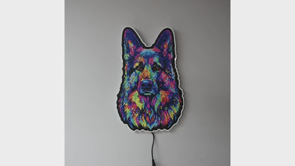 A colorful LED neon-style wall light  turned on and off shaped like a German Shepherd dog face, glowing with a multicolor neon pattern against a plain gray wall. 