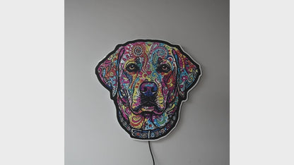 A colorful LED neon-style wall light shaped like an English Lab head, featuring a vibrant multicolor pattern on a black base, mounted against a dark gray wall with a warm glow around the edges when sign is turned on.