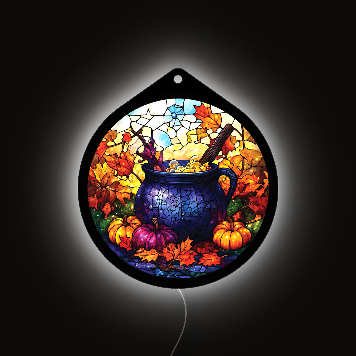 Witch's cauldron LED sign glowing on a wall, pumpkins and fall leaves lit up